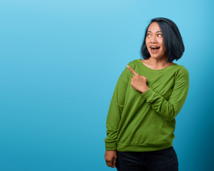 Woman on a blue background pointing to a left corner